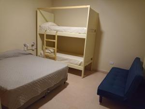 1 dormitorio con 2 literas y una silla azul en Privilegio Hostel en San Rafael