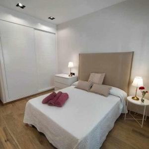 1 dormitorio con 1 cama blanca grande y 2 lámparas en Estupendo Piso Nuevo en Playa Victoria, en Cádiz