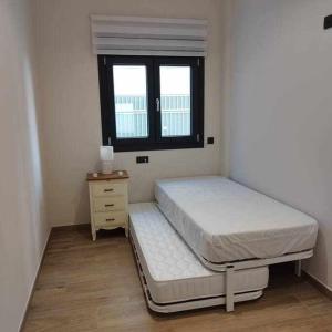 a small bedroom with a bed and a window at Estupendo Piso Nuevo en Playa Victoria in Cádiz