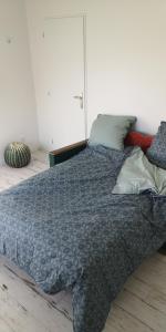 ein Bett mit blauer Decke in einem Schlafzimmer in der Unterkunft Ferme des Ormeaux 