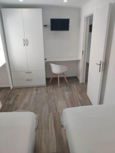 a white bedroom with a white cabinet and a chair at Casa da Avó Biza in São Roque do Pico