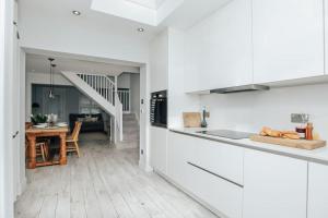 a kitchen with white cabinets and a dining room at Propeller house in Wargrave