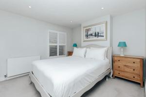 a white bedroom with a large bed and a dresser at Propeller house in Wargrave