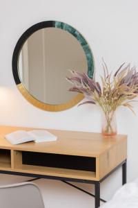Praga Duplex Apartment Premium Warsaw by Renters في وارسو: مرآة على رأس طاولة خشبية مع مزهرية