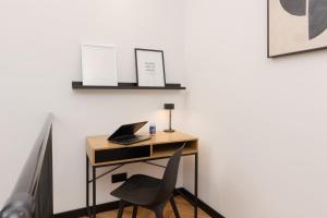 a desk with a laptop and a chair next to a wall at Praga Duplex Apartment Premium Warsaw by Renters in Warsaw
