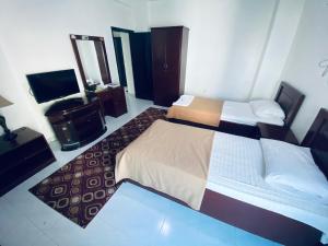 a hotel room with two beds and a television at PAN EMIRATES HOTEL APARTMENTS in Sharjah