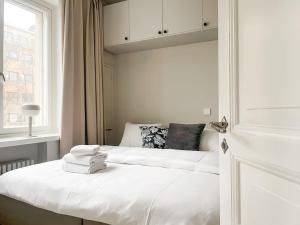 1 dormitorio con 2 camas con sábanas blancas y ventana en Central 1BR next to the park en Helsinki