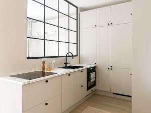 a kitchen with white cabinets and a sink and a window at Central 1BR next to the park in Helsinki