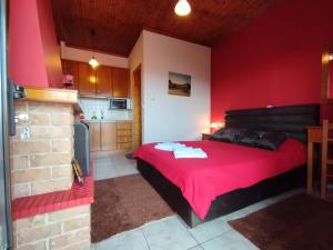 a red bedroom with a bed and a kitchen at Guesthouse Mythos in Orma