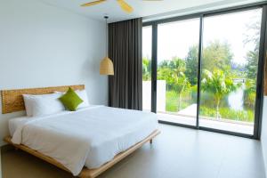 Un dormitorio con una cama blanca y una ventana grande. en VILLA 4 BEDROOMS SANCTUARY HO TRAM Private Pool 5 STARS, en Thuận Biên 100 fotos más