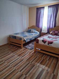 1 dormitorio con 2 camas y suelo de madera en Casa de campo Mostazal / Hogar para descansar, en El Rincón