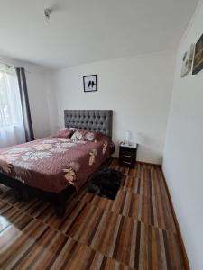 um quarto com uma cama e piso em madeira em Casa de campo Mostazal / Hogar para descansar em El Rincón
