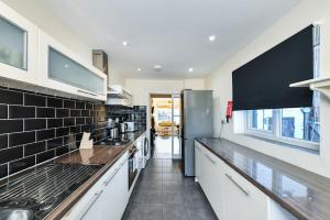 Hillside House في نوتينغهام: مطبخ مع خزائن بيضاء وجدار بلاط أسود