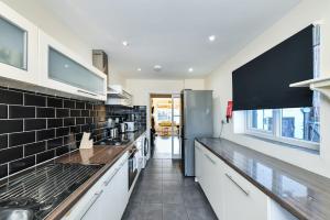 a kitchen with white cabinets and a black tile wall at Hillside House in Nottingham