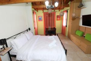 Schlafzimmer mit einem weißen Bett und einem TV in der Unterkunft Castle Maisonette in Chios