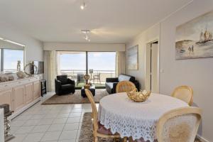 a living room with a table and chairs and a kitchen at seaview apartment margo in Blankenberge