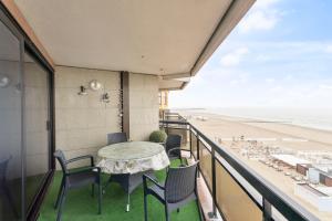a balcony with a table and chairs and the beach at seaview apartment margo in Blankenberge