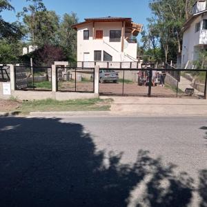 una valla al lado de una calle con una casa en COMPLEJO COMECHINGONES DPTO 3 2 HABITACIONES en Villa General Belgrano