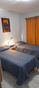 1 dormitorio con 1 cama y 1 mesa con lámpara en COMPLEJO COMECHINGONES DPTO 3 2 HABITACIONES en Villa General Belgrano