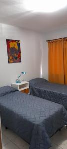 1 dormitorio con 2 camas y escritorio con lámpara en COMPLEJO COMECHINGONES DPTO 3 2 HABITACIONES en Villa General Belgrano
