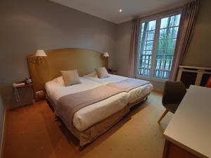 a bedroom with a large bed and a large window at Hotel Le Continental in Forges-les-Eaux