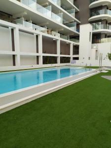 - une grande piscine dans un bâtiment doté d'une pelouse verdoyante dans l'établissement Apartamento Calpe Beach 1, à Calp