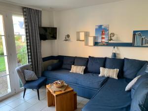 uma sala de estar com um sofá azul e uma mesa em Maison Fort-Mahon Plage Residence Belle Dune em Fort-Mahon-Plage