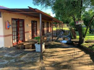 a building with a porch with tables and chairs at Eden Guest Farm in Bloemfontein