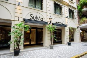 SuMa Recoleta Hotel في بوينس آيرس: مبنى sunoco أمامه أشجار نخيل