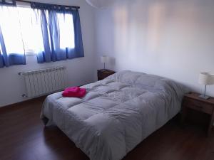 Un dormitorio con una cama con una bolsa rosa. en Tamy's House Casa compartida en Esquel