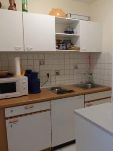 諾伊阿爾本羅伊特的住宿－Golf-Appartement Sonnenblick，厨房配有白色橱柜和微波炉