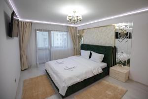 a bedroom with a large white bed with a green headboard at Apartament Gold in Târgu Ocna