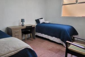 a bedroom with a bed and a desk with a blue blanket at Casa para viajes de descanso o de negocios in Quetzaltenango