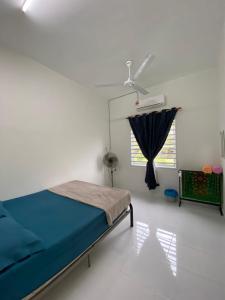 a bedroom with a bed and a window with a fan at Inap desa homestay batu buruk in Kuala Terengganu