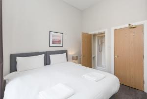 - une chambre avec un grand lit blanc et des oreillers blancs dans l'établissement Southside Apartments by Destination Edinburgh, à Édimbourg