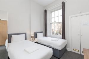 two beds in a room with a window at Southside Apartments by Destination Edinburgh in Edinburgh +101 photos