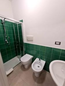 a green tiled bathroom with a toilet and a sink at La Finestrella in Belvedere Marittimo