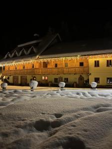 a building covered in snow at night with lights at Hotel ŠURC in Kranjska Gora