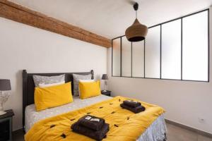 a bedroom with a large bed with yellow pillows at La Tour 1 Appartement au coeur du centre ville in LʼIsle-sur-la-Sorgue