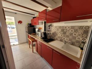 kuchnia z czerwonymi szafkami i zlewem w obiekcie Comme à la maison w mieście Marseillan