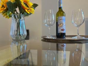 a bottle of wine and two glasses and a vase with flowers at Oakstays Forest Hall in Forest Hall