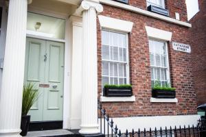 a brick house with a green door and two windows at Liverpool Georgian Town House Catharine St in Liverpool