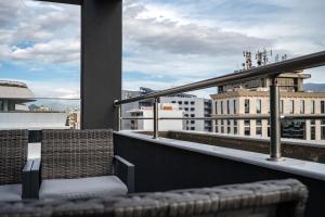 einen Balkon mit einem Stuhl und Blick auf die Gebäude in der Unterkunft Μεζονέτα με θέα στο πάρκο Σταύρος Νιάρχος ONE in Athen