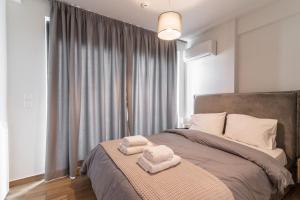 1 dormitorio con 1 cama con 2 toallas en Μεζονέτα με θέα στο πάρκο Σταύρος Νιάρχος ONE, en Atenas