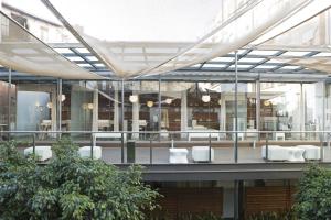 un grand bâtiment en verre avec des tables et des chaises blanches dans l'établissement Hospes Palau de La Mar, à Valence