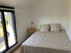 a white bedroom with a bed with a window at Maison neuve spacieuse port et plages à pied in Ploudalmézeau