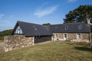 una casa de piedra con techo negro en Large farmhouse with garden and sea view for 8 people en Locquénolé