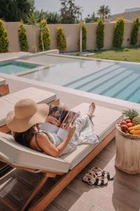 a woman laying on a couch next to a swimming pool at Marble Luxury Suites in Karteros
