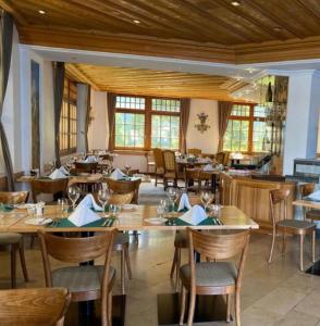 a restaurant with wooden tables and chairs and windows at De France by Thermalhotels in Leukerbad