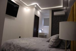 a white bedroom with a bed and a television at Luxurious and Central Apartment 2Br in Xalapa